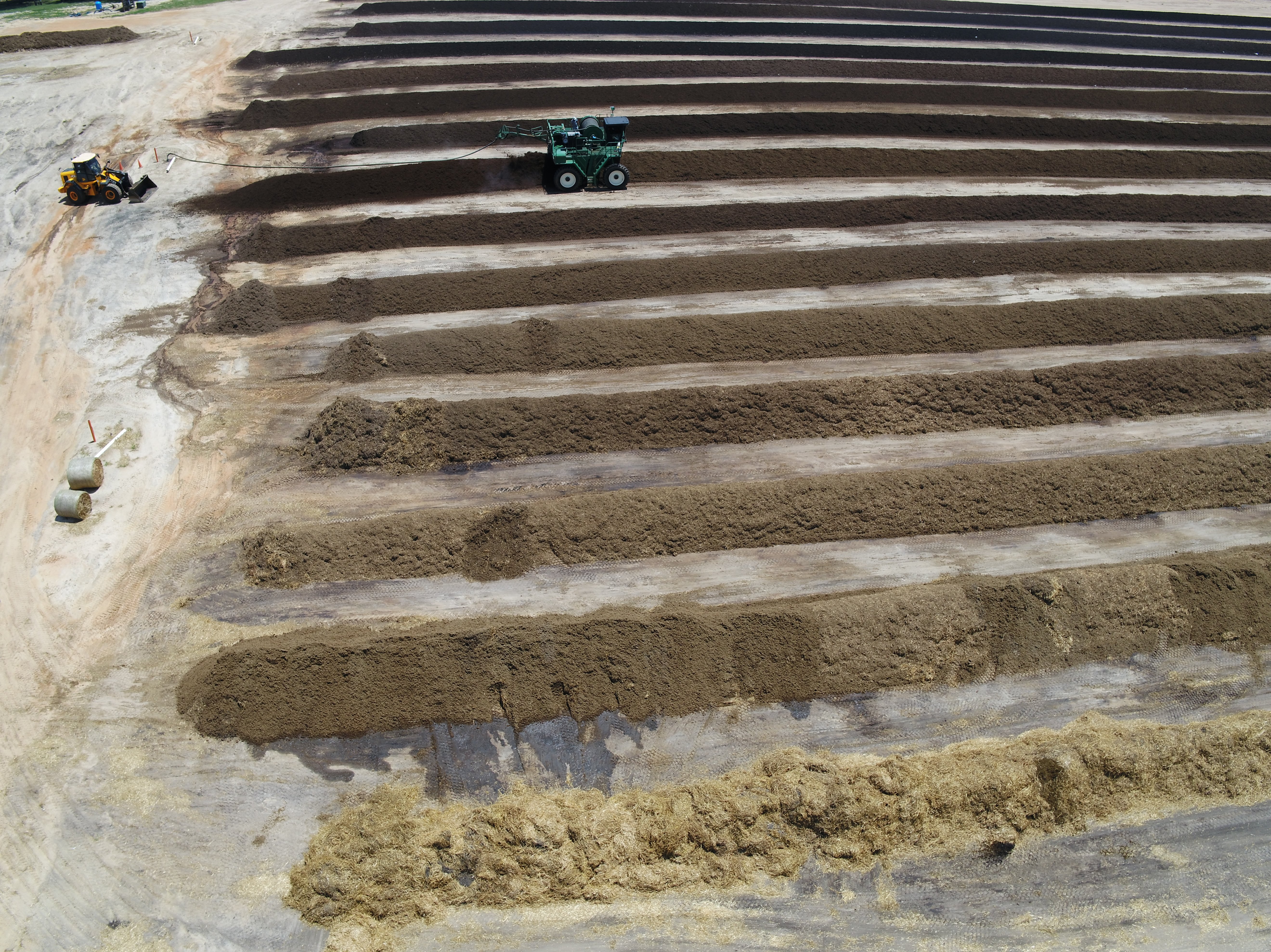 Windrows of compost with farm equipment